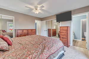 Bedroom featuring ensuite bath, light hardwood / wood-style flooring, ceiling fan, and a closet