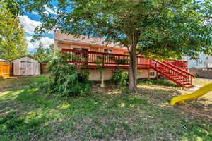 Rear view of house featuring a wooden deck and a storage shed