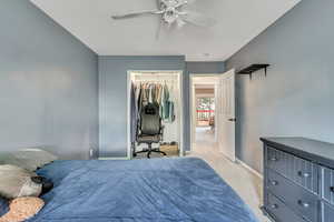 Carpeted bedroom with ceiling fan, a walk in closet, and a closet