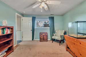 Bedroom with light carpet, a textured ceiling, and ceiling fan