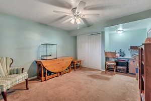 Bedroom with a textured ceiling, light colored carpet, and ceiling fan