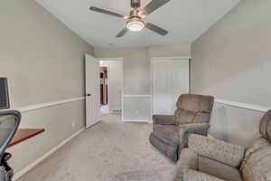 Living area featuring light colored carpet and ceiling fan