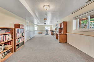 Interior space featuring a textured ceiling, wood walls, and light carpet