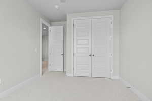 Unfurnished bedroom featuring carpet, baseboards, and a closet