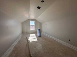 Bonus room with a textured ceiling and vaulted ceiling