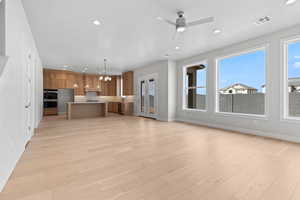 Kitchen featuring brown cabinets, light countertops, visible vents, open floor plan, and light wood-type flooring