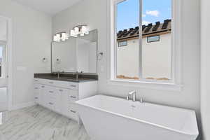 Bathroom featuring marble finish floor, double vanity, a sink, and a wealth of natural light