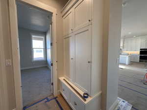 Mudroom featuring light colored carpet and a textured ceiling