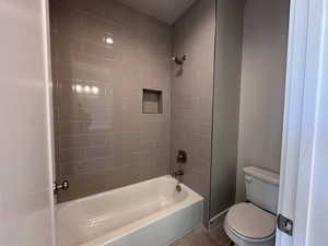 Bathroom featuring toilet, tile patterned floors, and tiled shower / bath