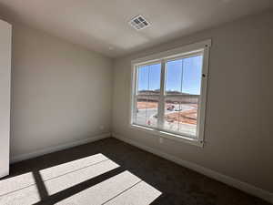 Empty room featuring dark colored carpet