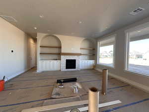 Living room with built in shelves, a fireplace, and a textured ceiling