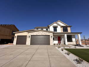 View of front of house with covered porch, a garage, and a front lawn