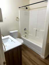 Bathroom featuring wood finished floors, toilet, shower / bathing tub combination, and vanity