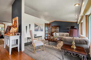 Living room featuring crown molding, vaulted ceiling, and hardwood / wood-style flooring