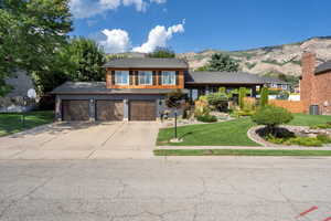 View of front of home with a mountain view, a front yard, and a garage