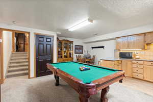 Playroom with pool table, light colored carpet, and a textured ceiling