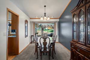 Dining space featuring crown molding, light colored carpet, and a notable chandelier