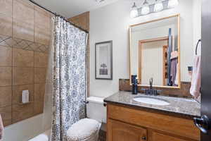 Full bathroom featuring a textured ceiling, vanity, toilet, and shower / bath combo with shower curtain