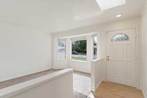 Foyer entrance featuring light hardwood / wood-style flooring, a skylight, and ornamental molding