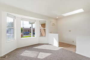 Empty room with a skylight and light hardwood / wood-style flooring