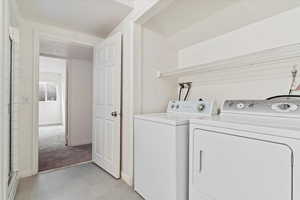 Clothes washing area featuring light carpet and washing machine and clothes dryer