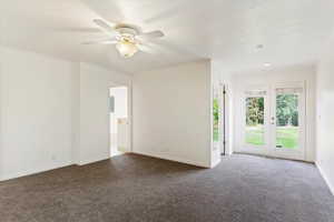 Carpeted empty room featuring ceiling fan, crown molding, and french doors