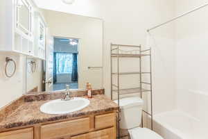 Full bathroom with vanity, toilet, tub / shower combination, and ceiling fan