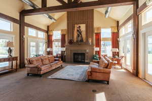 Carpeted living room with a tiled fireplace, french doors, beamed ceiling, and high vaulted ceiling