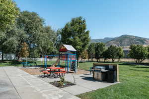 View of playground featuring a lawn and a mountain view