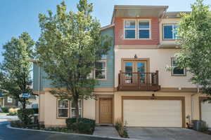 View of property featuring a garage, a balcony, and central AC unit