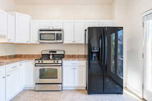 Kitchen featuring light tile patterned floors, stainless steel appliances, and white cabinetry