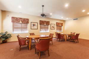 Carpeted dining room featuring ceiling fan