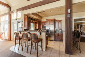 Kitchen featuring tasteful backsplash, light tile patterned floors, kitchen peninsula, appliances with stainless steel finishes, and a breakfast bar area