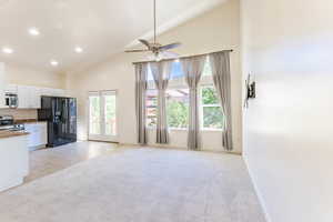 Kitchen with white cabinetry, gas stove, ceiling fan, lofted ceiling, and black fridge