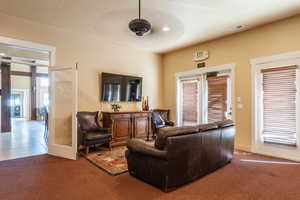 Carpeted living room with ceiling fan