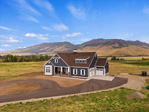 View of front of home featuring a mountain view, covered porch, a rural view, and a garage