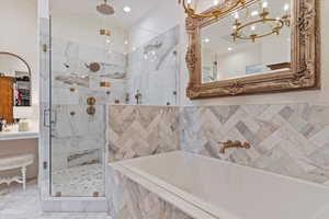 Bathroom featuring a chandelier and separate shower and tub