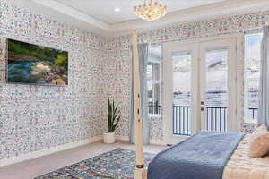 Bedroom featuring an inviting chandelier, carpet flooring, access to exterior, ornamental molding, and a tray ceiling