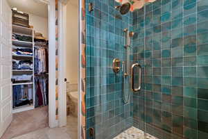 Bathroom with tile patterned flooring, toilet, and a shower with door