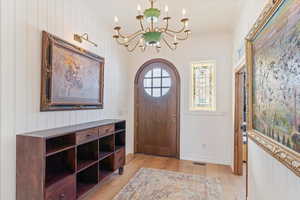 Foyer entrance featuring light hardwood / wood-style flooring, an inviting chandelier, and ornamental molding