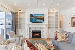 Living room featuring a fireplace, light wood-type flooring, built in features, and wooden ceiling