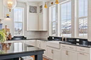 Kitchen with white cabinetry, plenty of natural light, decorative light fixtures, and sink