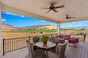 Wooden terrace featuring outdoor lounge area, a mountain view, ceiling fan, and a rural view