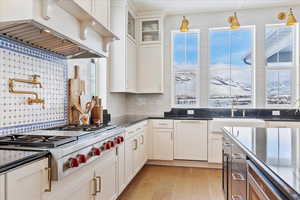 Kitchen with a mountain view, tasteful backsplash, light hardwood / wood-style flooring, and white cabinetry