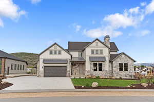 View of front of property featuring a mountain view, a garage, and a front lawn