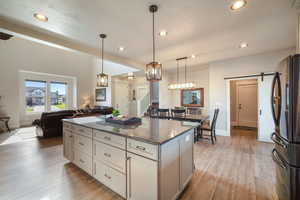 Kitchen featuring a barn door, black fridge, dark stone countertops, and light hardwood / wood-style flooring