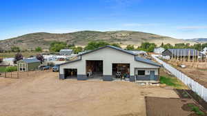 Rear view of property with a mountain view and a storage unit