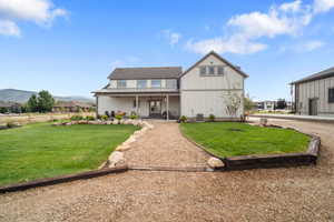 View of front of house with a mountain view, a patio area, and a front lawn