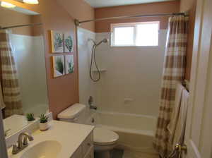 Hall bathroom featuring toilet, shower / tub combo, and vanity