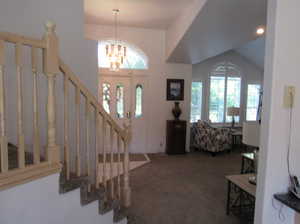 Carpeted entrance foyer with lofted ceiling and an inviting chandelier